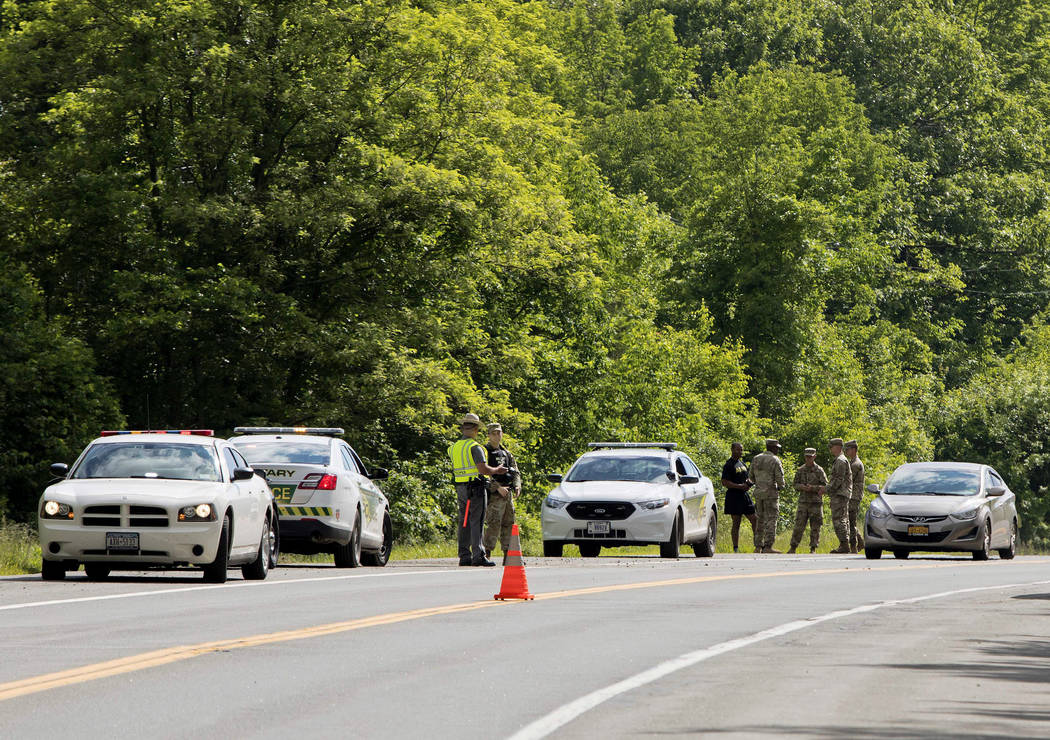 Military police and civilian first responders stand along Route 293 in response to a rollover o ...