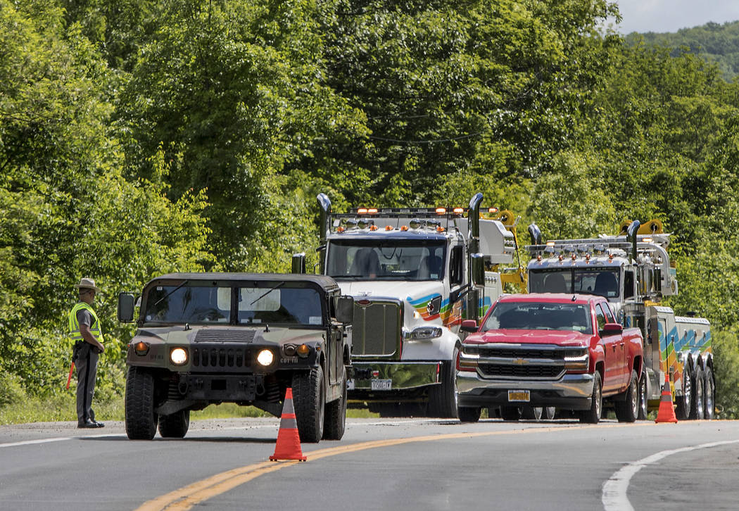 Military police direct traffic along Route 293 near the site where an armored personnel vehicle ...