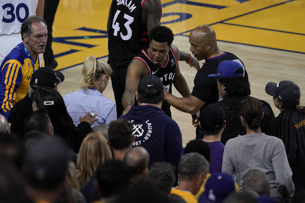 Toronto Raptors guard Kyle Lowry, middle, gestures next to referee Marc Davis (8) near the fron ...