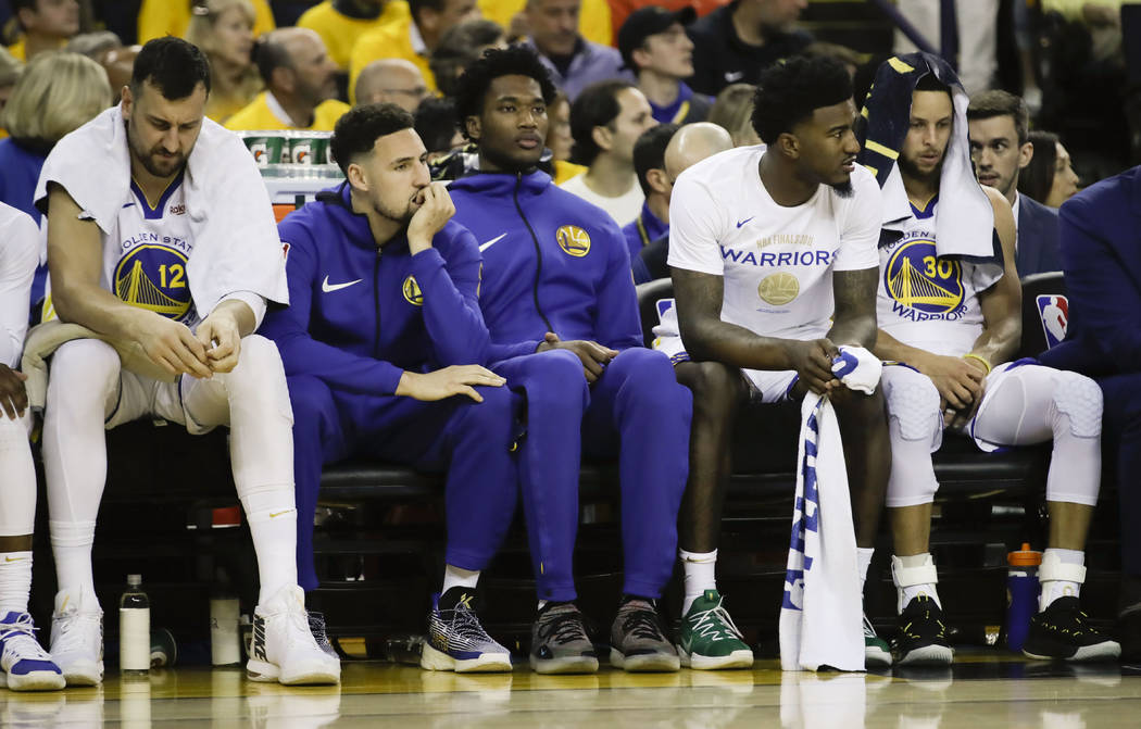 Golden State Warriors guard Klay Thompson, second from left, sits on the bench with teammates d ...