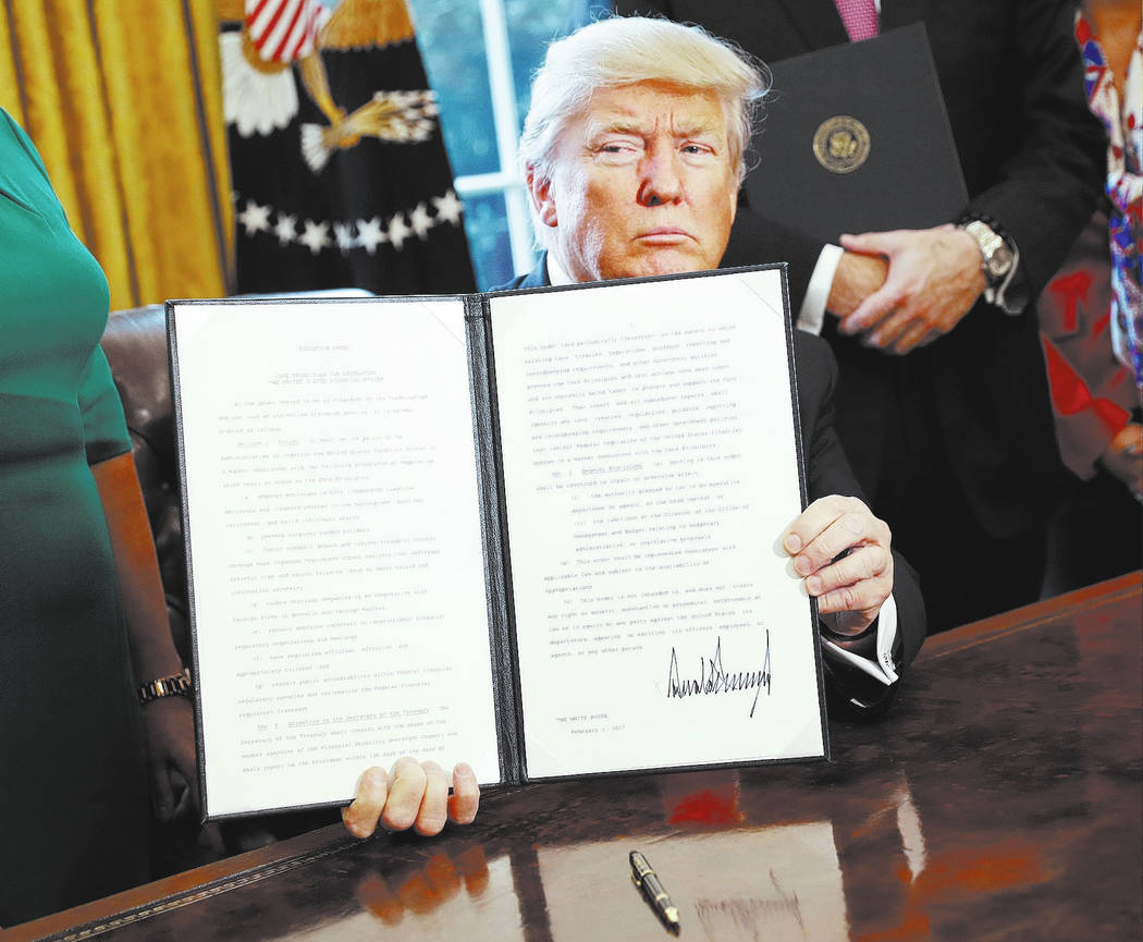 President Donald Trump holds up an executive order after his signing the order in the Oval Offi ...