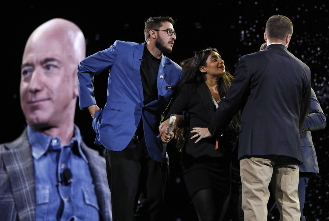 Security removes a protestor, second from left, from the stage as Amazon CEO Jeff Bezos speaks ...