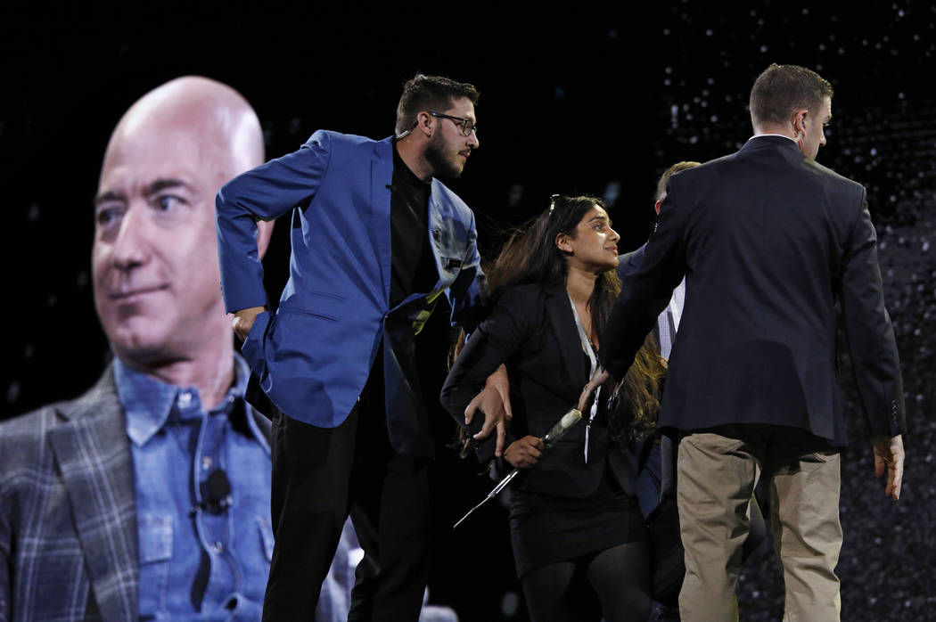 Security removes a protestor, second from left, from the stage as Amazon CEO Jeff Bezos speaks ...