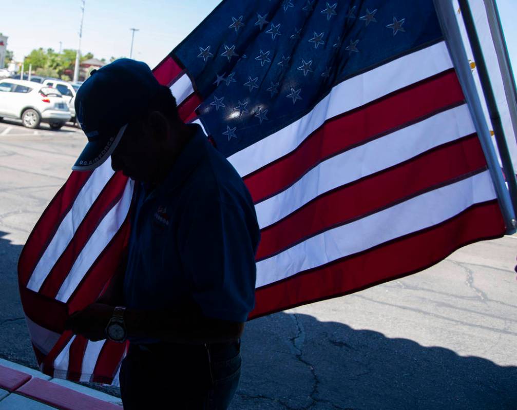 Alex Pena, 60, from the Philippines, fixes the end of an American flag before the annual celebr ...