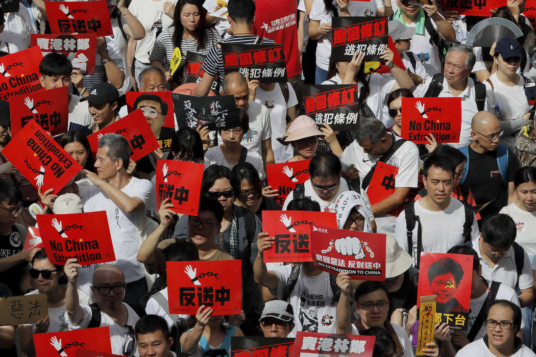 Protesters hold placards march in a rally against the proposed amendments to extradition law in ...