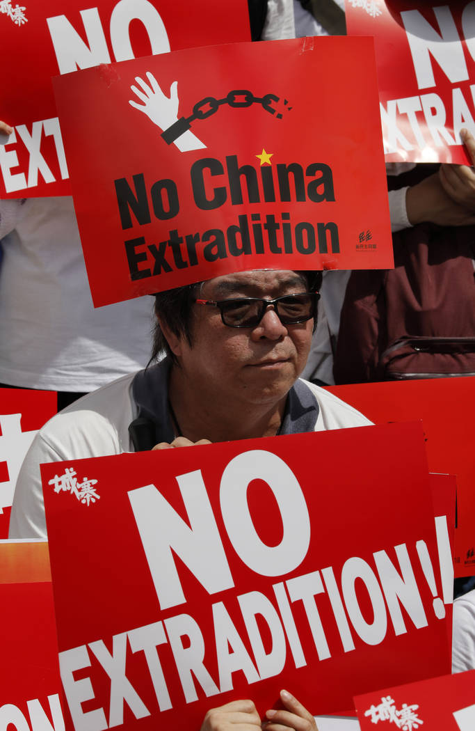 A man raises placards as ten of thousands of protesters march along a downtown street to agains ...