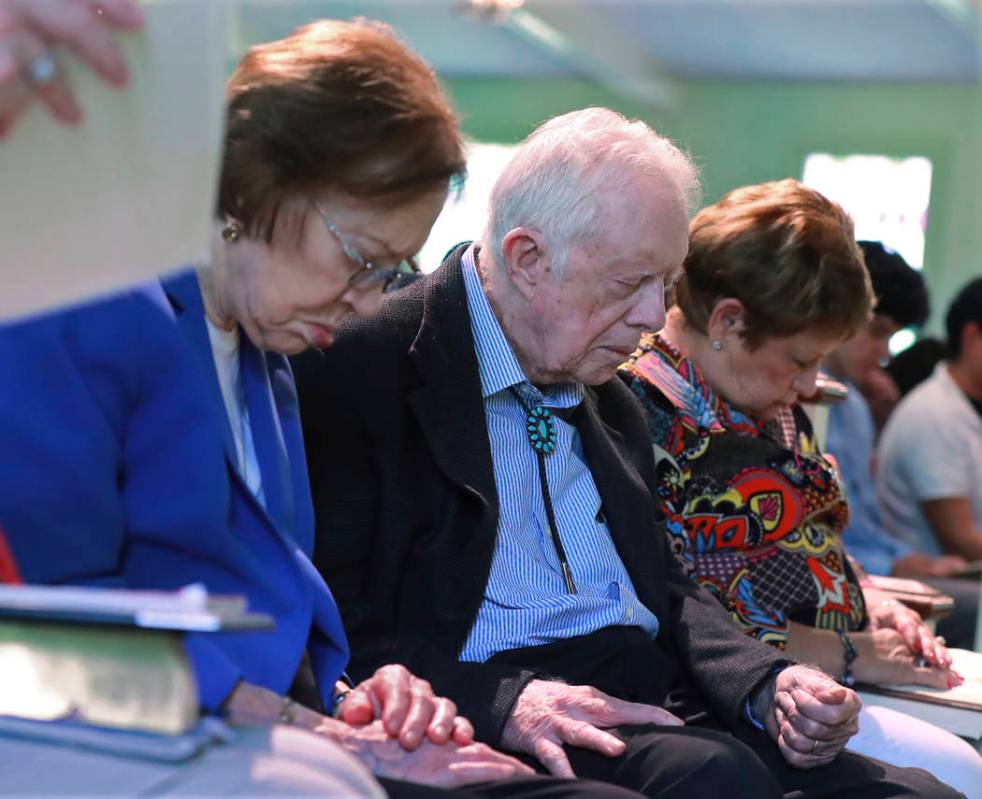 President Jimmy Carter and Rosalynn Carter bow their heads in prayer with members and visitors ...