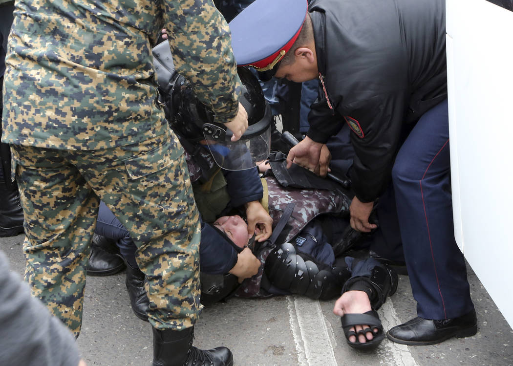 Kazakh police officers try to help their comrade during an anti-government protest during the p ...