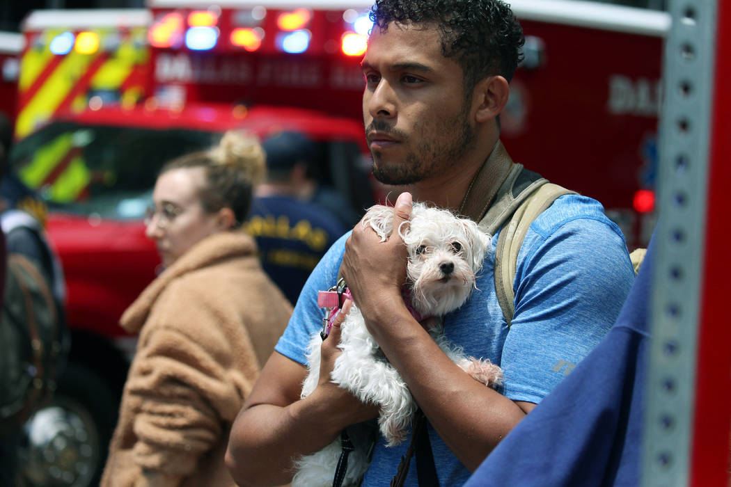 Isaiah Allen, a resident of the damaged apartments, holds onto Princess, as he watches official ...