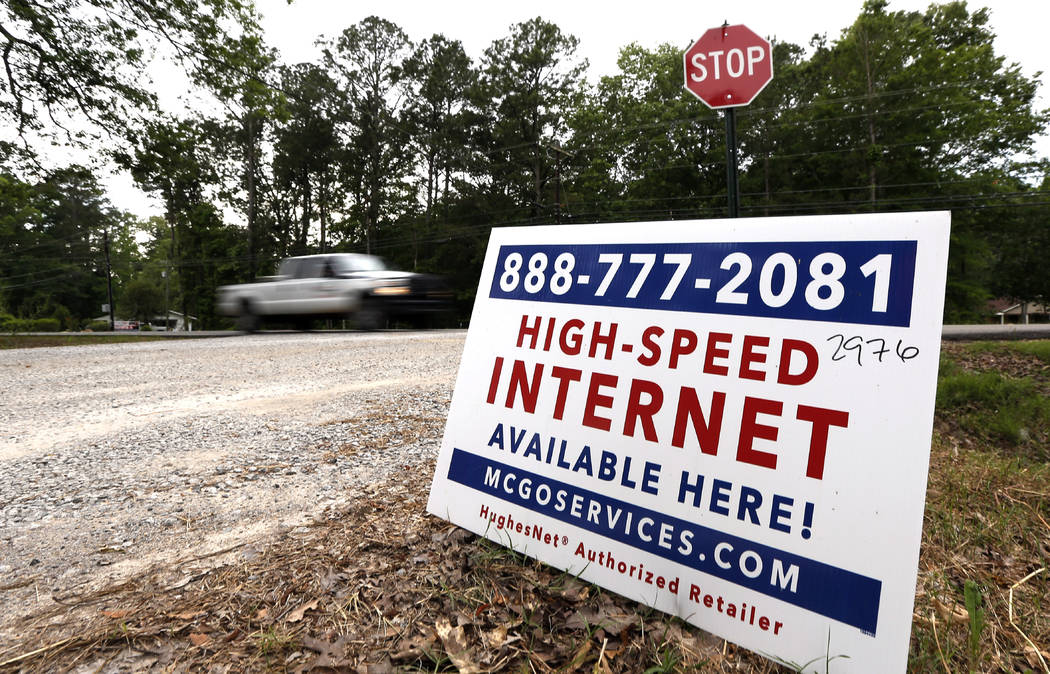 In this May 8, 2019, photo, a car drives past a sign advertising high-speed internet service ne ...