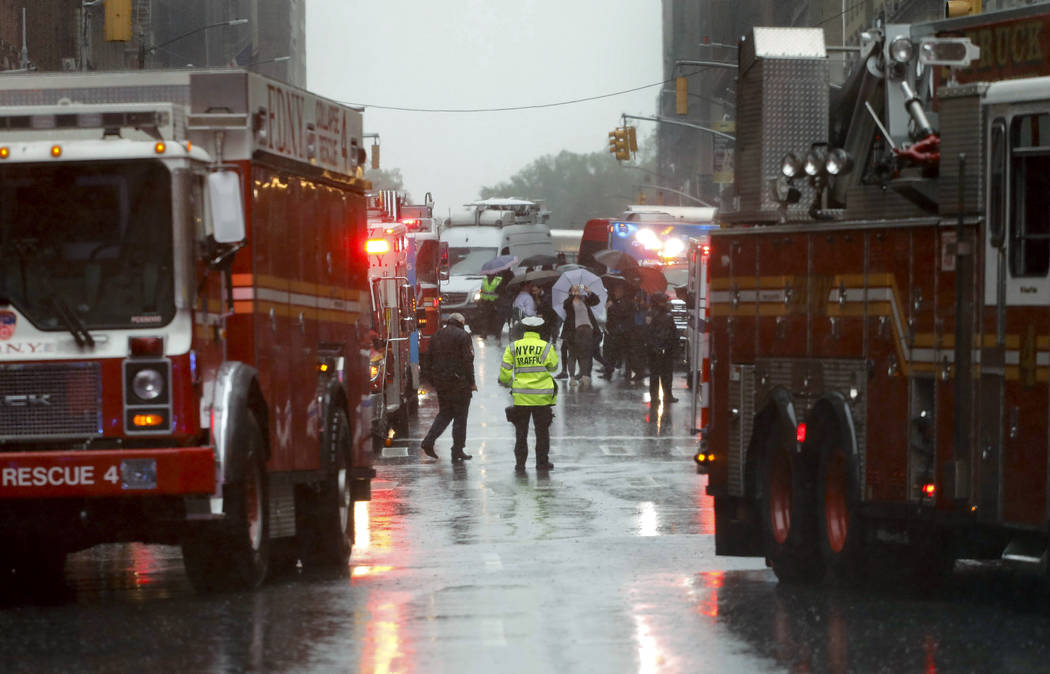 First responders arrive near the scene where a helicopter crash-landed on the roof of a midtown ...