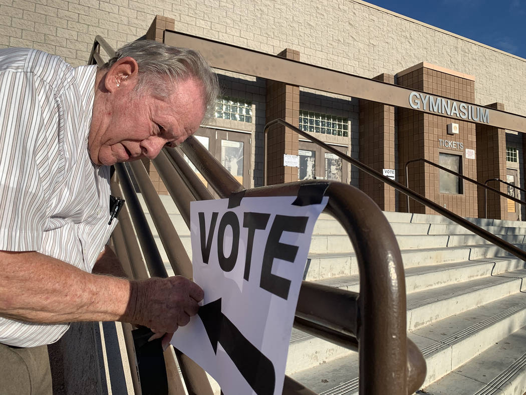 Poll worker Donald Somerville tapes up a sign for municipal elections at Bonanza High School in ...