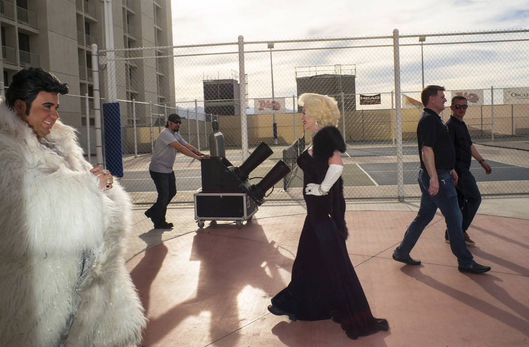 Costumed performers dressed as Liberace and Marilyn Monroe walk by a confetti cannon before the ...