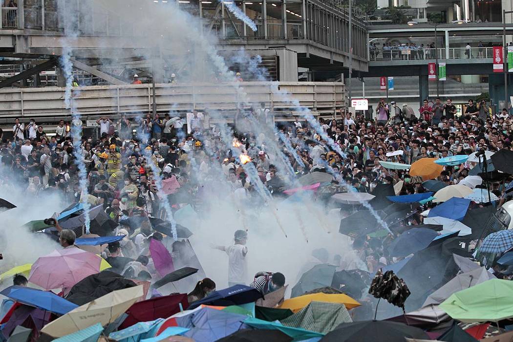 In this Sunday, Sept. 28, 2014, file photo, riot police launch tear gas into the crowd as thous ...