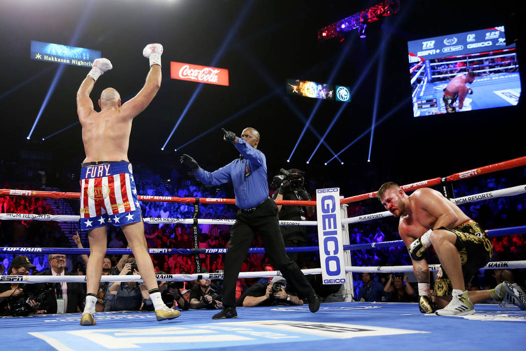 Tyson Fury, left, reacts after knocking down Tom Schwarz in the second round of the lineal heav ...