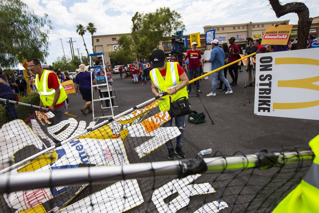 Workers prepare a sign while protesting in support of higher minimum wage outside of McDonald's ...