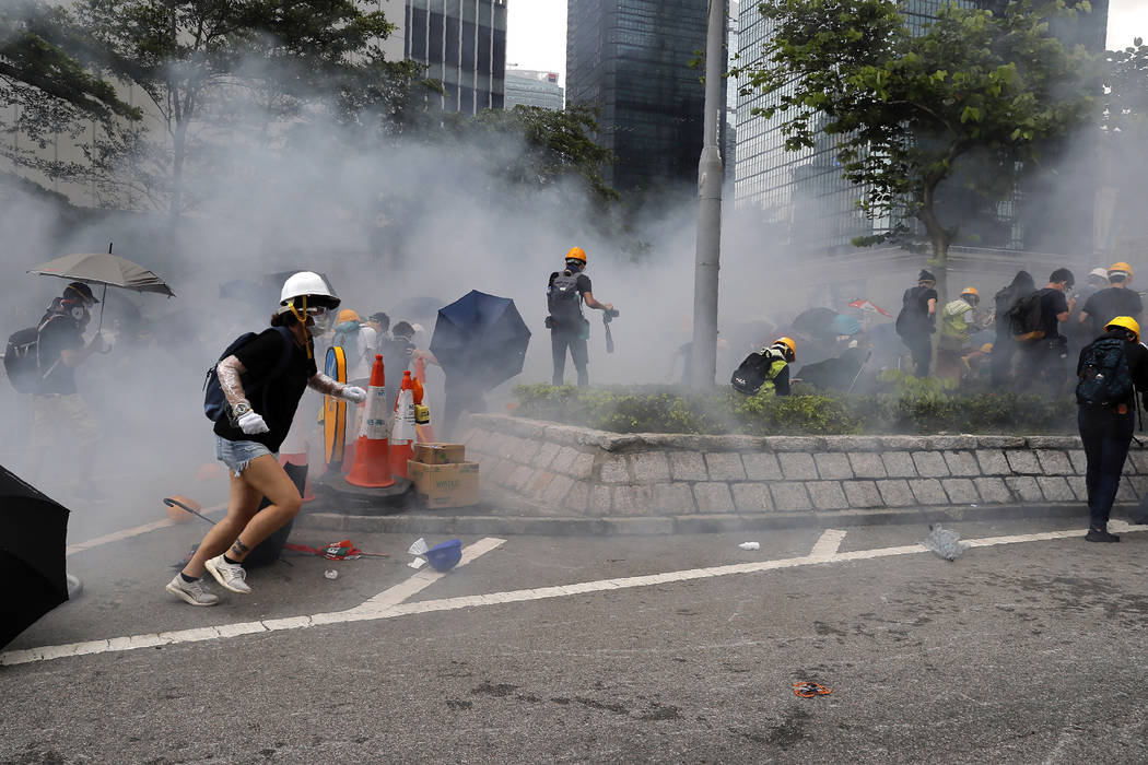 Protesters react to tear gas during a large protest near the Legislative Council in Hong Kong, ...