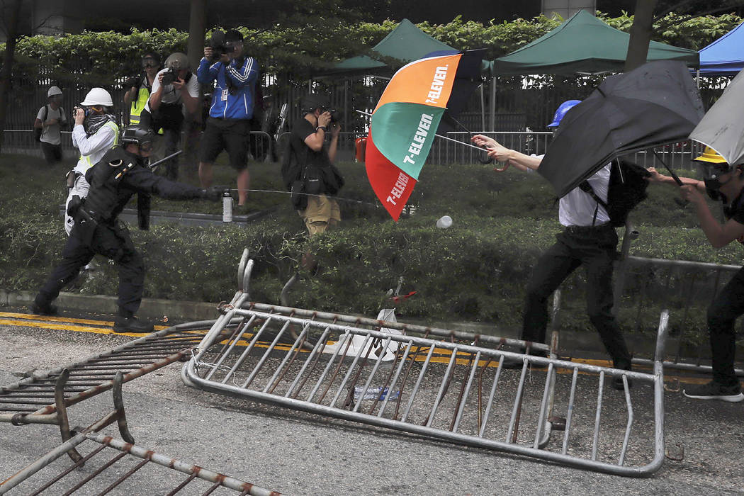 A police officer sprays pepper spray at protesters near the Legislative Council in Hong Kong, W ...