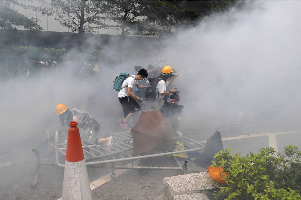 Protesters react to a cloud of tear gas near the Legislative Council in Hong Kong, Wednesday, J ...