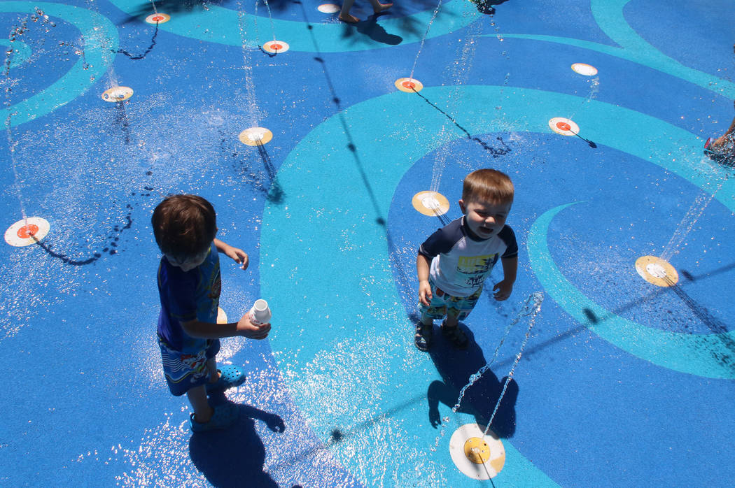 Children, including Caleb Lugrand, 2, right, of Las Vegas play at a splash pad on a hot day at ...