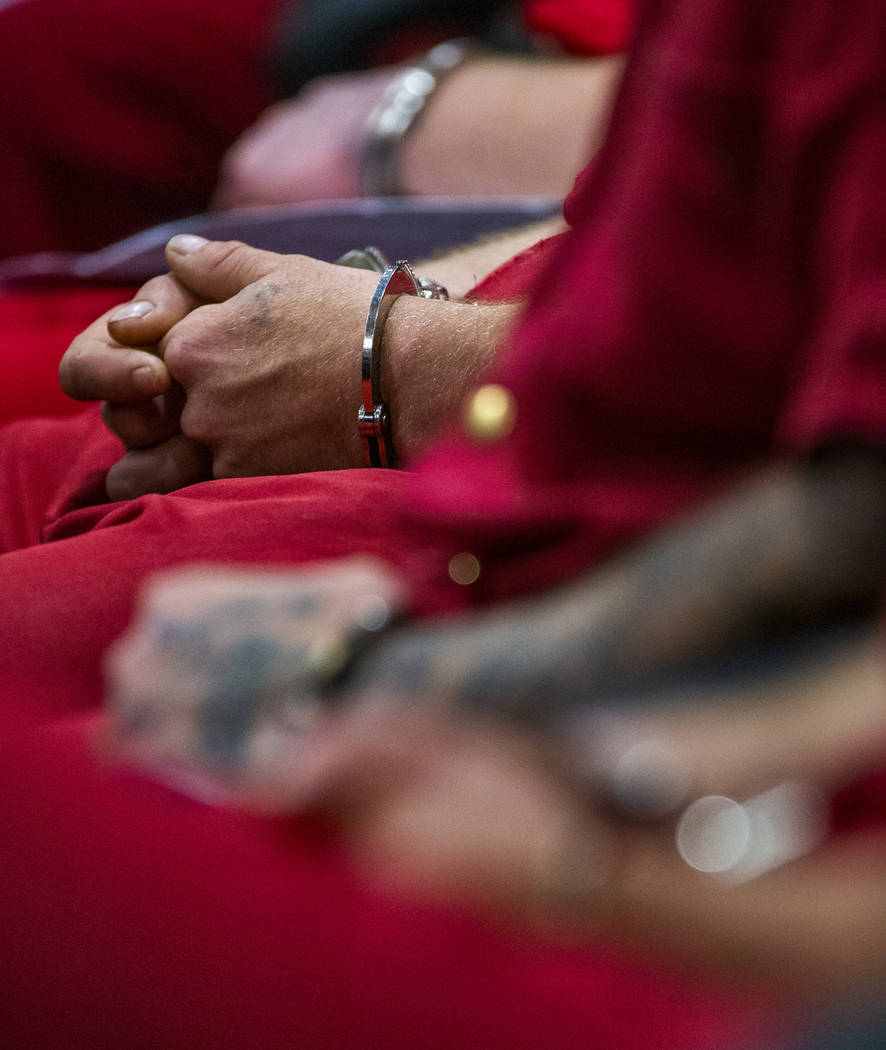 Defendants sit in hand cuffs before the judge while appearing in Henderson Justice Center court ...