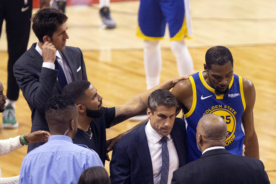 Golden State Warriors forward Kevin Durant, right, is consoled by Drake as he walks off the cou ...