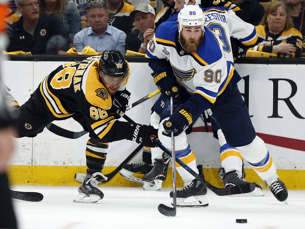 St. Louis Blues' Ryan O'Reilly (90) moves the puck away from Boston Bruins' David Pastrnak, lef ...