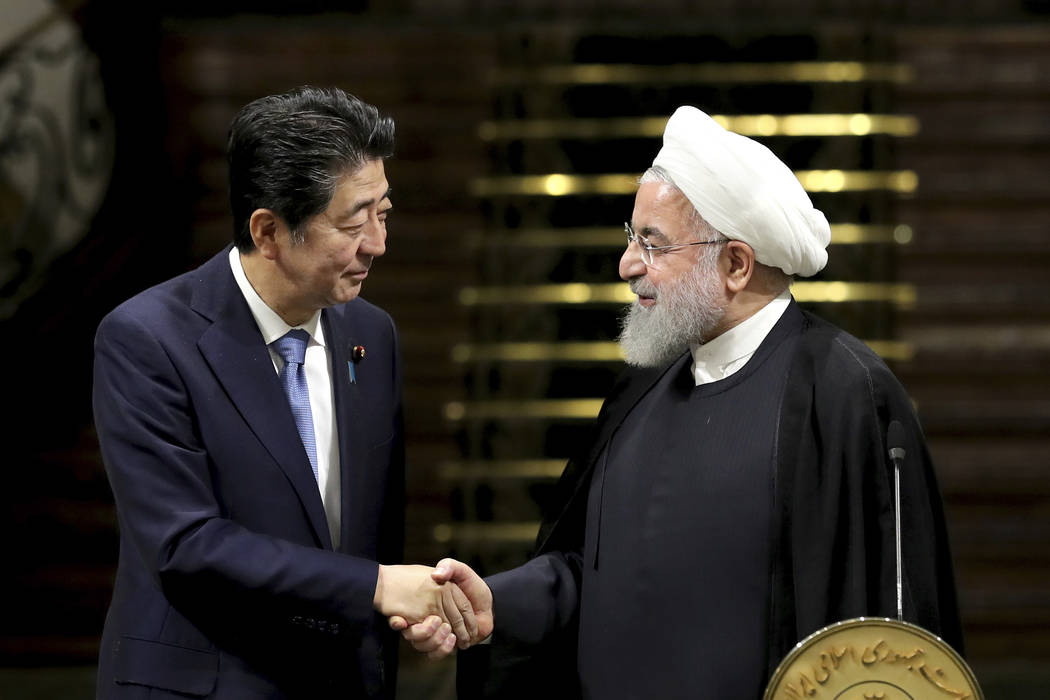 Japanese Prime Minister Shinzo Abe, left, and Iranian President Hassan Rouhani shake hands afte ...