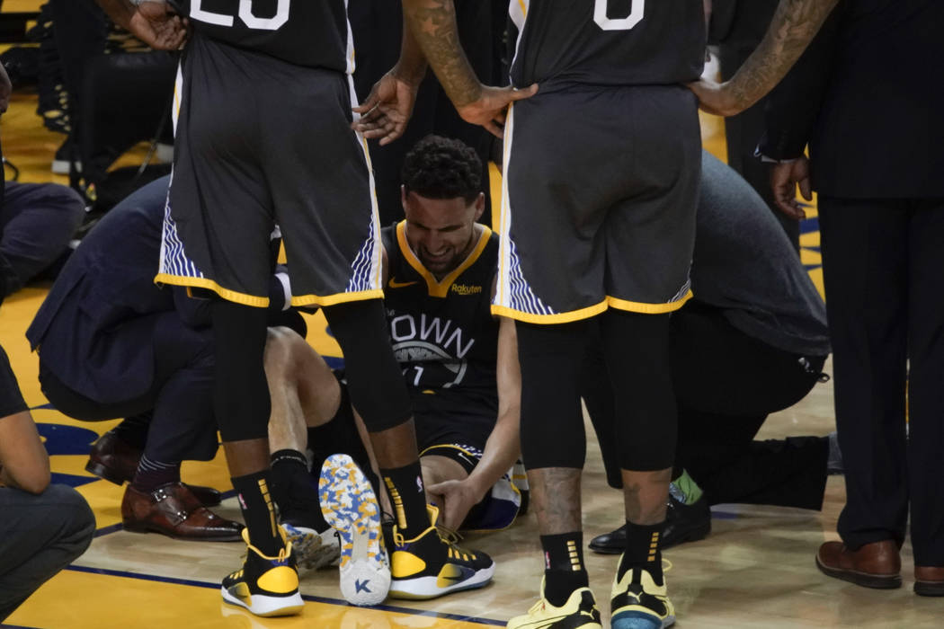 Golden State Warriors guard Klay Thompson, center, is helped up after being injured during the ...