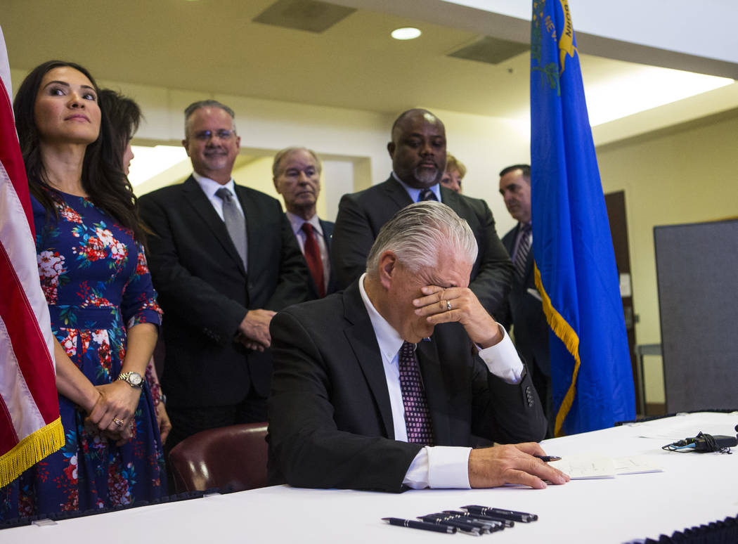 Gov. Steve Sisolak pauses for a moment before signing a trio of bills, including AB291, which i ...