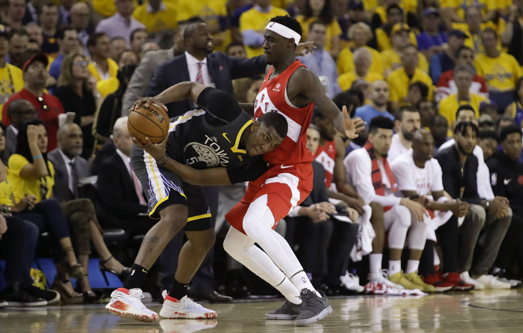 Golden State Warriors center Kevon Looney (5) is defended by Toronto Raptors forward Pascal Sia ...