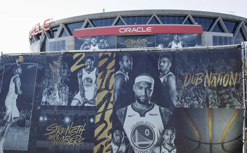 A sign showing images of Golden State Warriors players is displayed outside of Oracle Arena bef ...