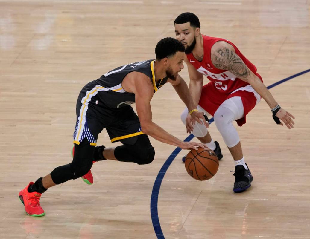 Golden State Warriors guard Stephen Curry, left, dribbles against Toronto Raptors guard Fred Va ...