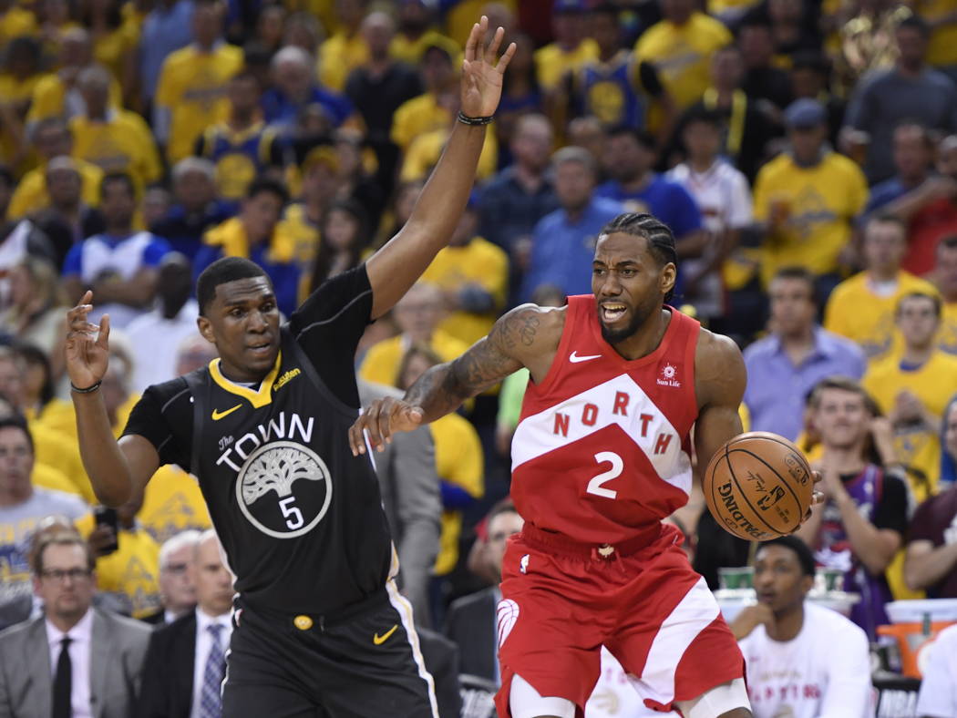 Toronto Raptors forward Kawhi Leonard (2) moves past Golden State Warriors centre Kevon Looney ...