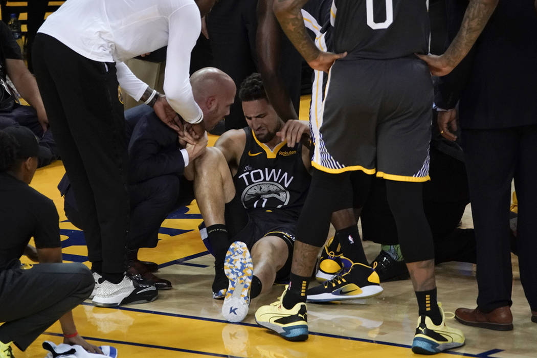 Golden State Warriors guard Klay Thompson, center, is helped up after being injured during the ...