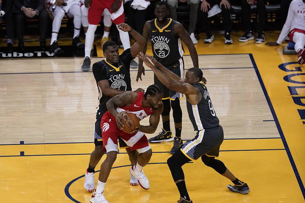 Toronto Raptors forward Kawhi Leonard, middle, is defended by Golden State Warriors center Kevo ...