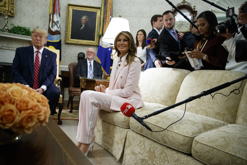 President Donald Trump looks on as first lady Melania Trump talks with reporters during a meeti ...