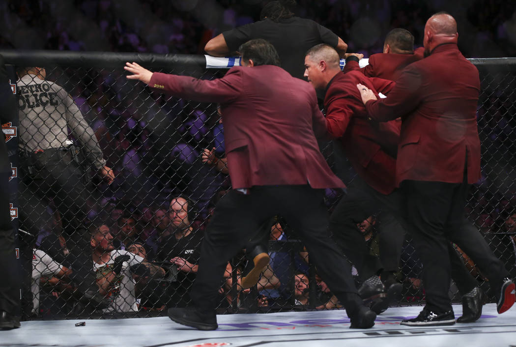 Members of security chase after Khabib Nurmagomedov after he jumped out of the octagon followin ...