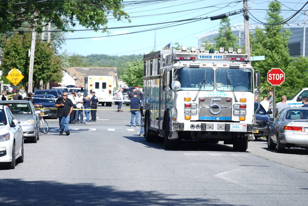 New York City Police officials gather along Wilcox Street behind the 121st Precinct station hou ...