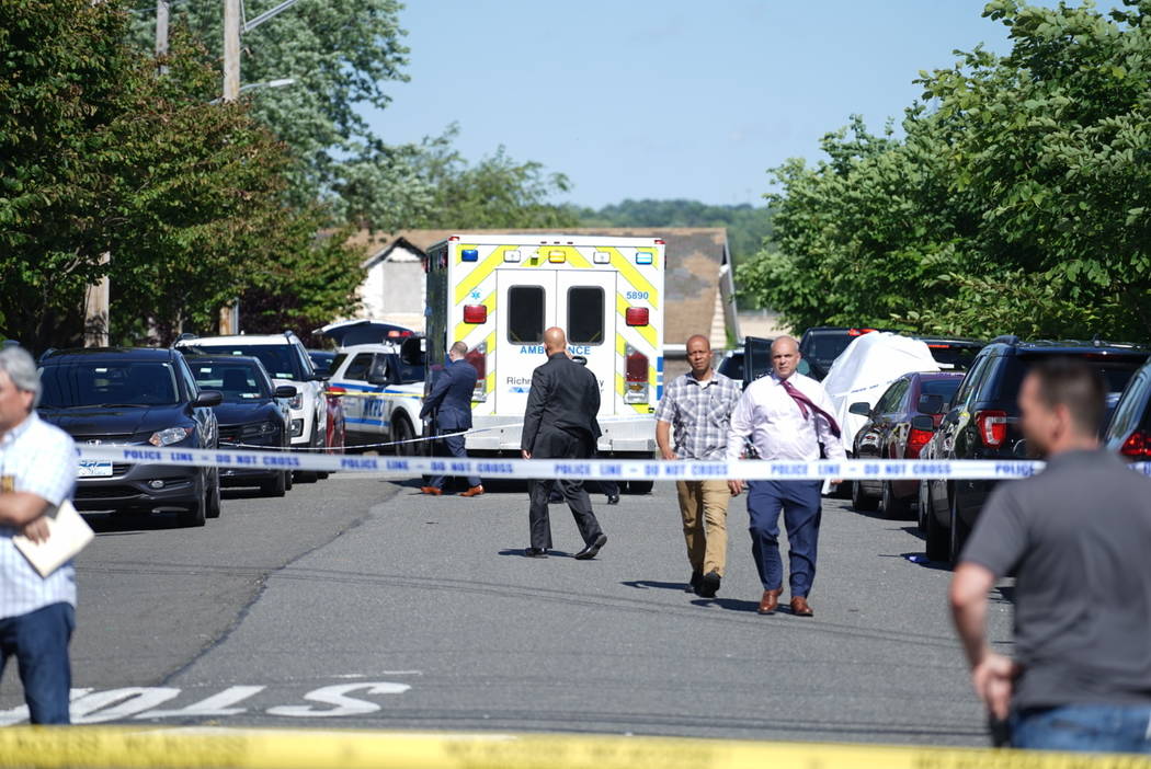 New York City Police officials gather along Wilcox Street behind the 121st Precinct station hou ...