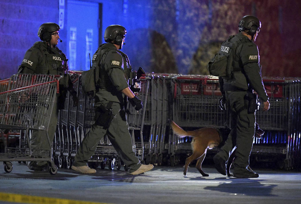 Heavily armed police officers exit the Corona Costco following a shooting inside the wholesale ...