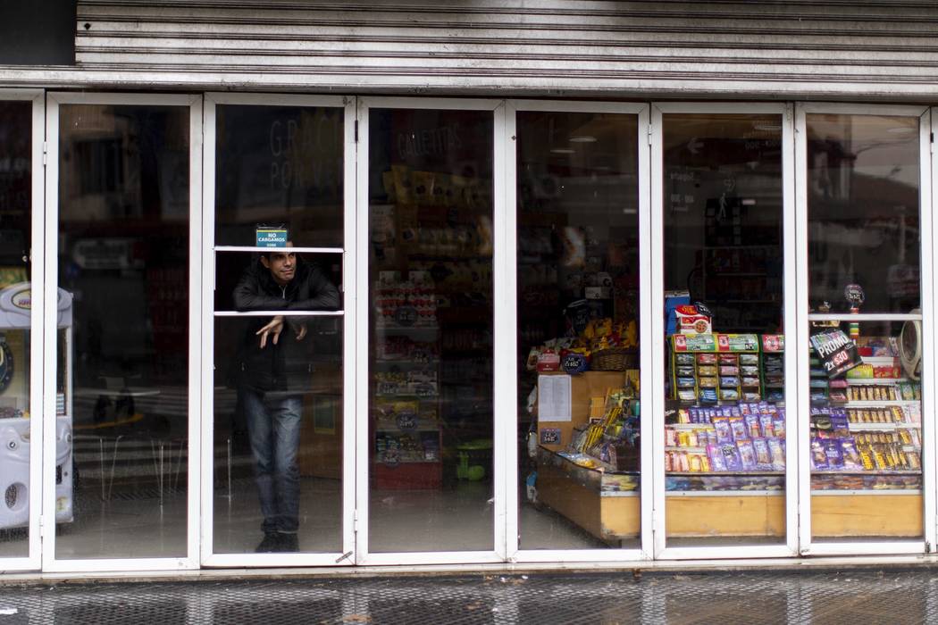 A man stands inside a store without power during a blackout, in Buenos Aires, Argentina, Sunday ...