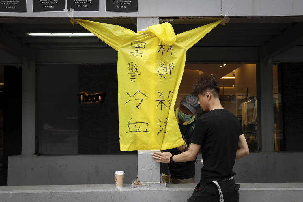 Protesters place a raincoat bearing the words "Cold blooded black police, Carrie Lam kill ...