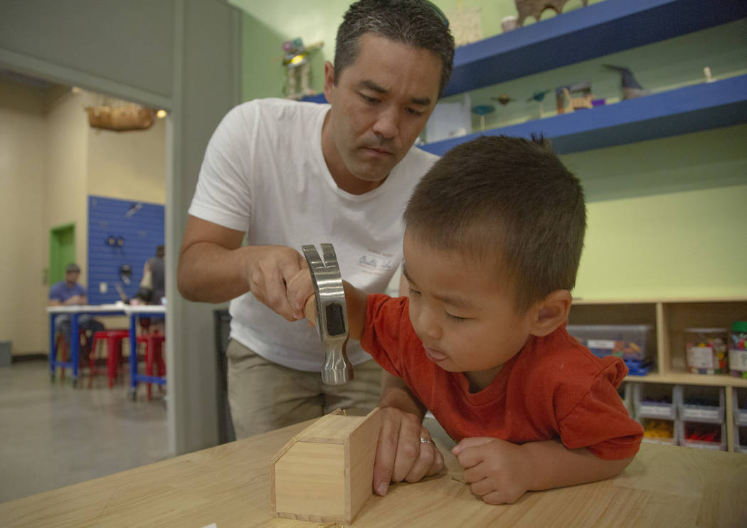 Garrett Clanin, 37, from Hawaii and Kai Clanin, 3, fix a wooden figure during an event to celeb ...