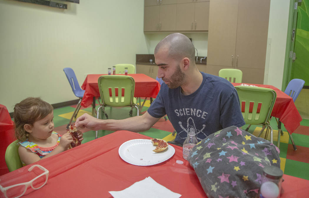 Phillip Castanon of Las Vegas, right, shares a piece of a jelly bagel with his daughter Emilia, ...