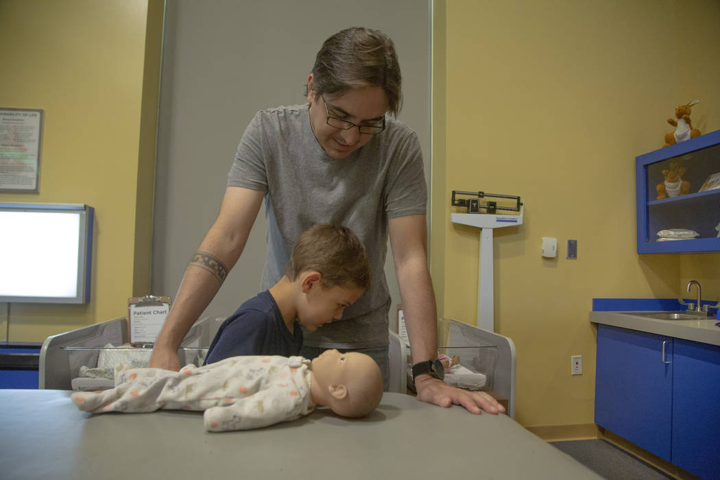 Darren Trentacoste, watches as his son Lucious, 5, learn how to pamper a baby doll at Discovery ...