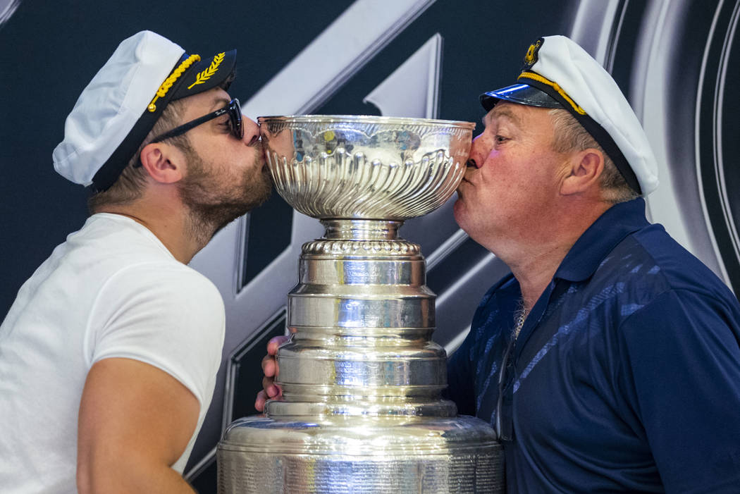 Fans Christian St. Pierre and his father Guy of Ottawa, Canada, kiss the Stanley Cup, the most ...