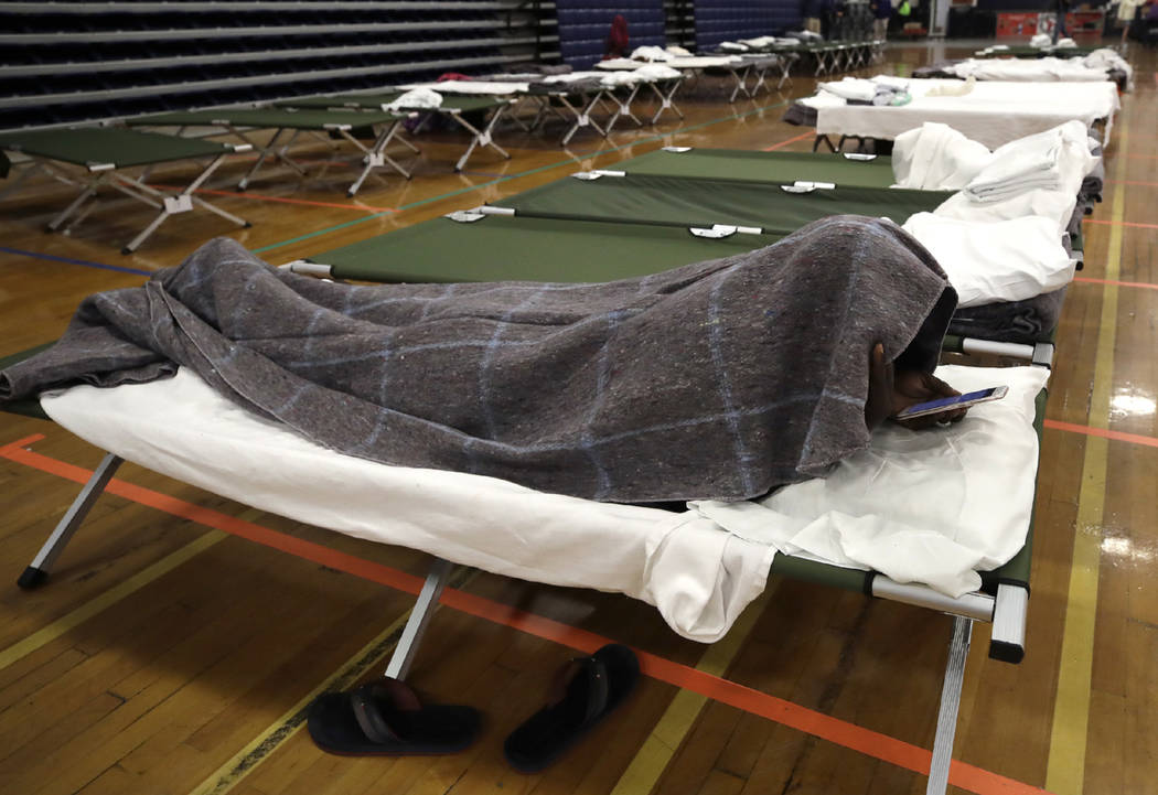 A migrant man looks at his cellphone as he rests inside the Portland Exposition Building, in Po ...