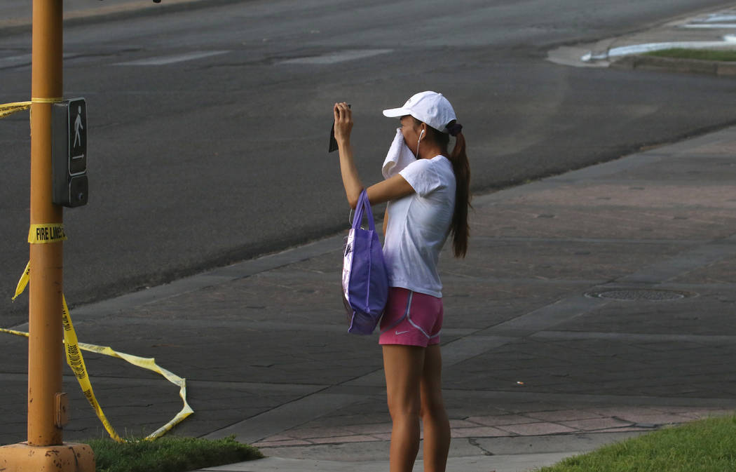 A woman covers her face to protect herself from smoke as she takes a photo at The Park 3900 at ...