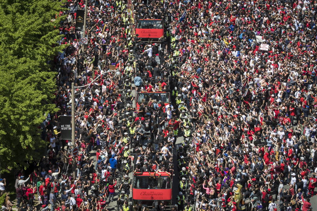 Members of the Toronto Raptors NBA basketball championship team ride on buses during a victory ...